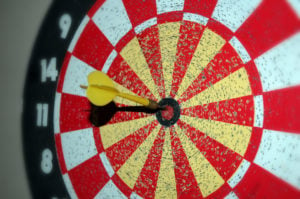 black, red and white dart board with yellow dart stuck in the middle