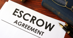 escrow agreement on a wood table with book, pen, and eyeglasses