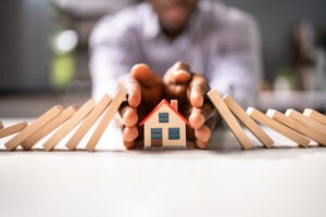 toy house with dominos and a man's hands around it